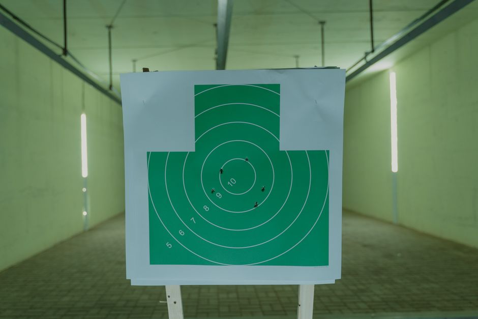 A green circle target with bullet holes at an indoor shooting range, ideal for practice visuals.