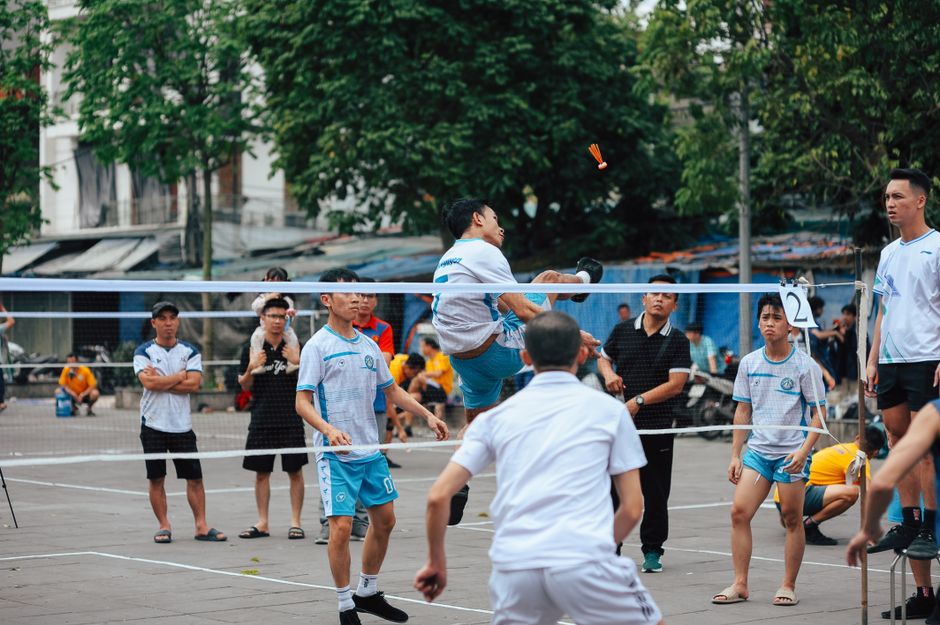 Dynamic outdoor sepak takraw game with athletes in mid-action.